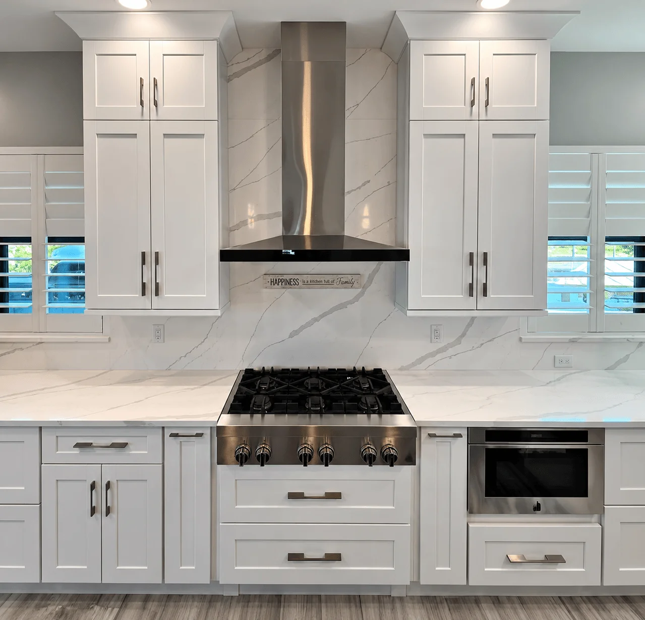 White kitchen with marble backsplash and stainless range hood